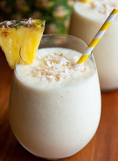 Easy 3 ingredient Piña Colada smoothie in a glass with a tropical backdrop