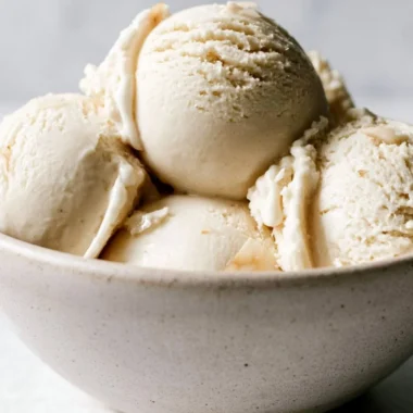 Homemade coconut ice cream served in a bowl with a coconut on the side