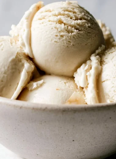 Homemade coconut ice cream served in a bowl with a coconut on the side