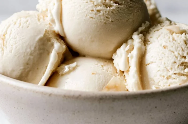Homemade coconut ice cream served in a bowl with a coconut on the side