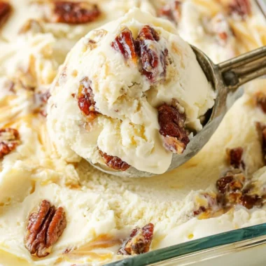 Bowl of homemade buttered pecan ice cream with toasted pecans on top.