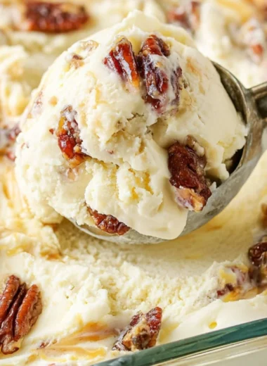 Bowl of homemade buttered pecan ice cream with toasted pecans on top.