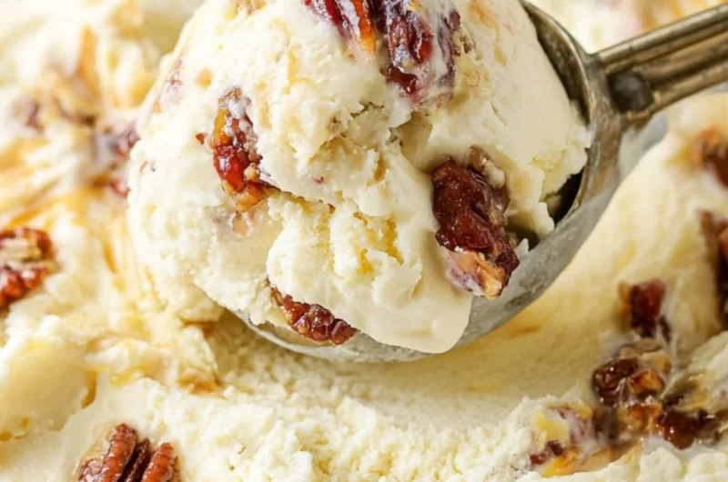Bowl of homemade buttered pecan ice cream with toasted pecans on top.
