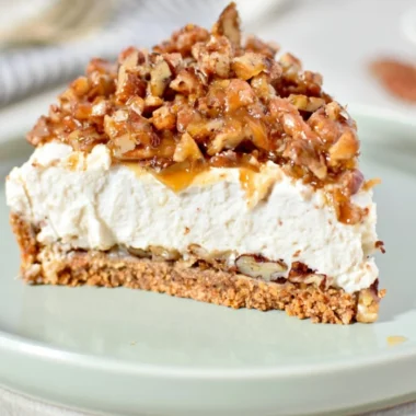 No-bake keto pecan pie cheesecake topped with pecans and caramel drizzle