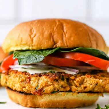 Cozy chickpea cauliflower burger topped with fresh veggies on a plate.