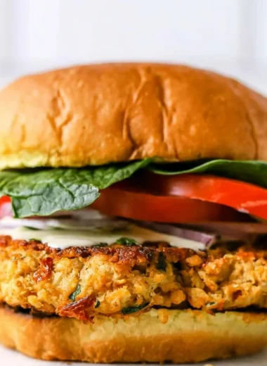 Cozy chickpea cauliflower burger topped with fresh veggies on a plate.