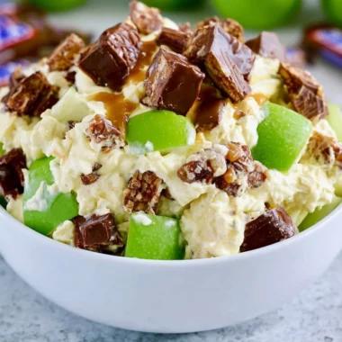 Delicious Snickers Apple Salad with apples, caramel, and whipped cream in a bowl.
