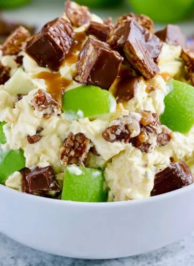 Delicious Snickers Apple Salad with apples, caramel, and whipped cream in a bowl.