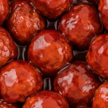 Crockpot Meatballs cooked in grape jelly and BBQ sauce served in a bowl.
